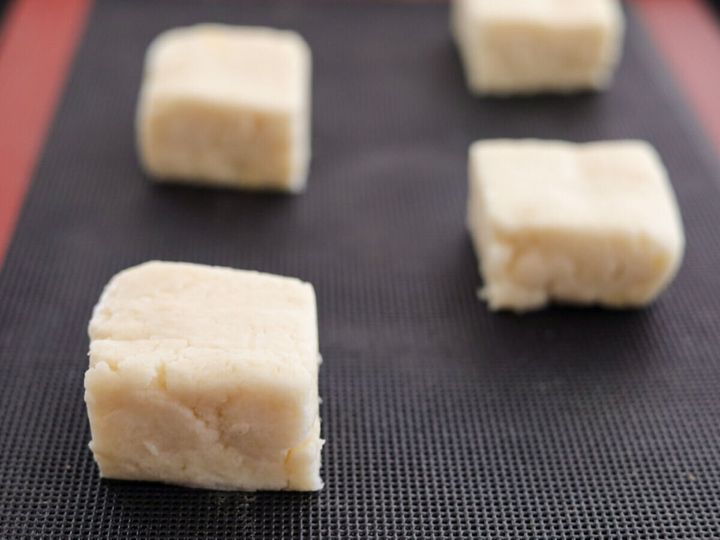 黒いシリコンマットが敷かれた天板に、4つにカットされた四角いスコーン生地が並べられている
