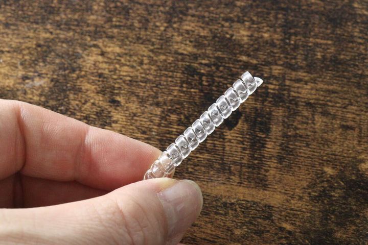 指で透明なキズ防止コイルを一本つまんでいる様子