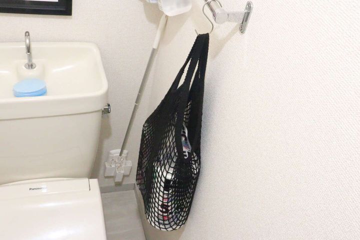 トイレの壁に吊るされたネットバッグにトイレットペーパーが収納されている