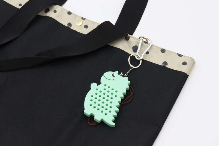 黒いバッグの持ち手に取り付けられたティラノサウルス型キーホルダー