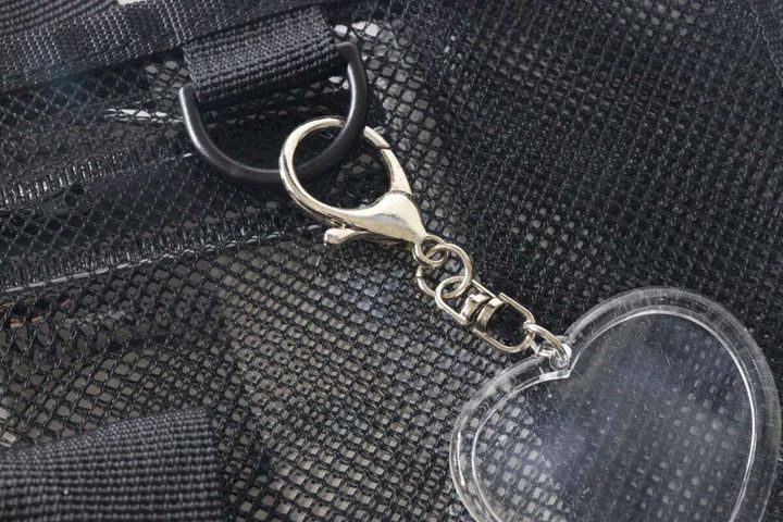 メッシュバッグのDカンにハート型の透明なキーホルダーが取り付けられている。