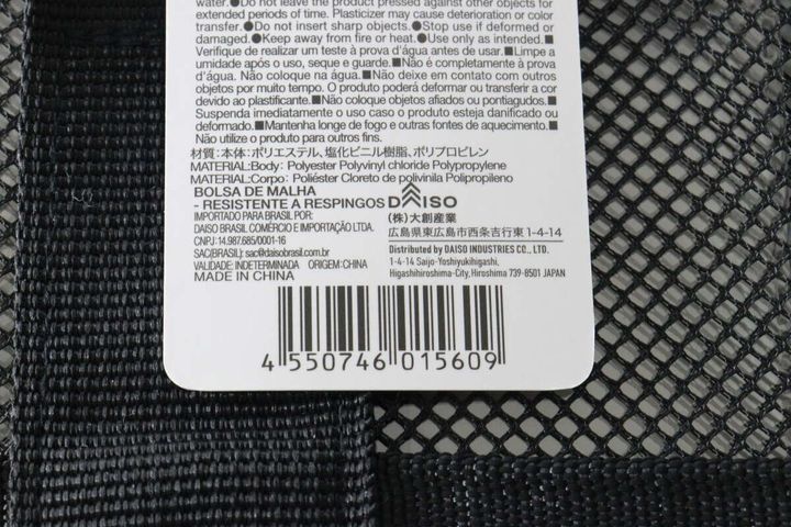 黒いメッシュバッグに付いている商品タグのクローズアップ。JANコードや素材が記載されている。
