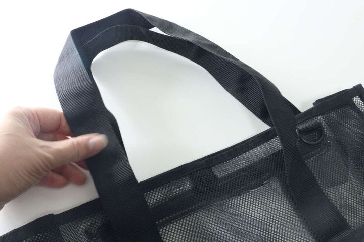 メッシュバッグの太くしっかりとした持ち手を片手で持っている様子。