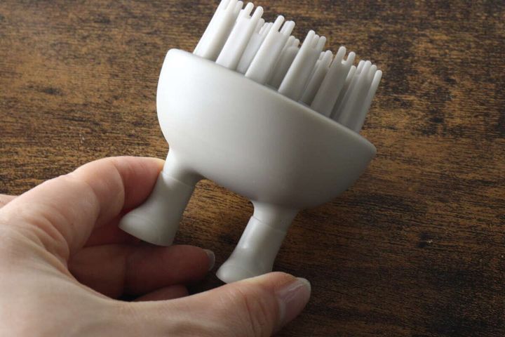 手に持ったグレーの足で立つシャンプーブラシ