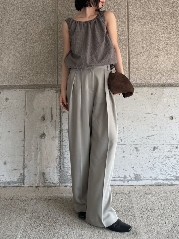 くすみベージュのノースリーブとワイドパンツの女性