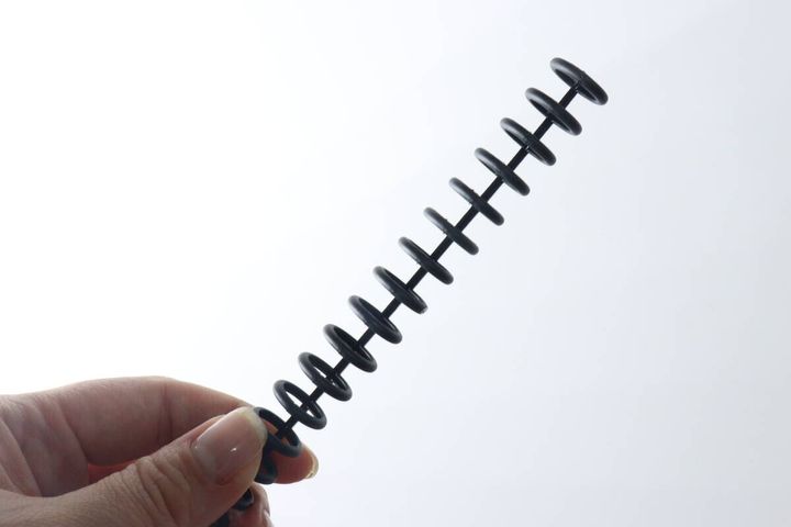 女性の指が黒いカラー30リングの柔らかさを確認するように持っている