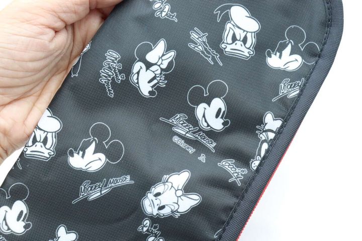 手が黒い折りたたみ傘用収納袋のミッキー＆フレンズ柄を指している。キャラクターのアップ。