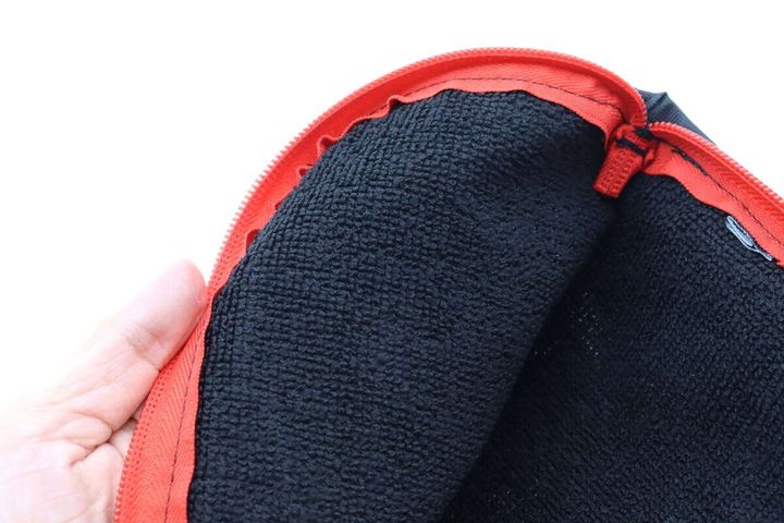 手が折りたたみ傘用収納袋の内側を見せている。黒いマイクロファイバー生地がはっきりと見える。