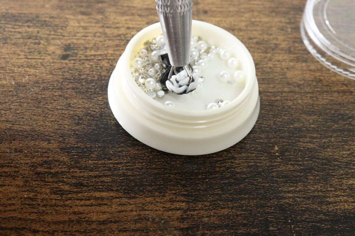 ペン型ツールでケース内の小さなネイルパーツを掴んでいる