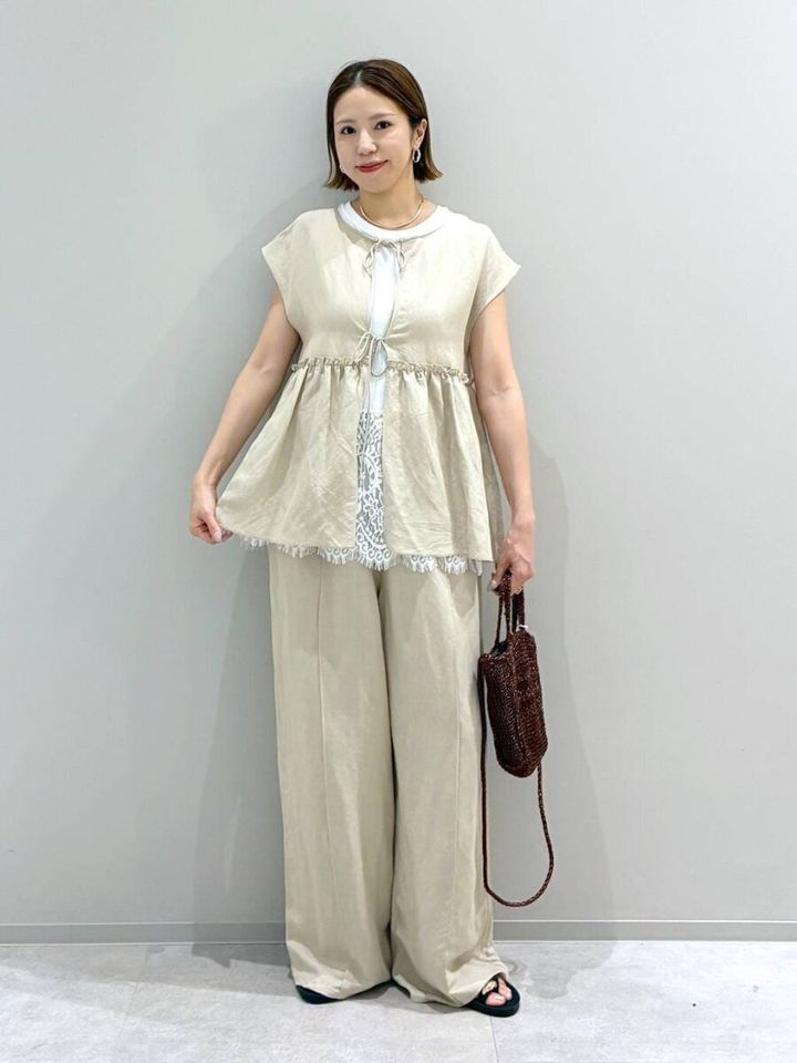 ベージュのペプラムブラウスとパンツの女性