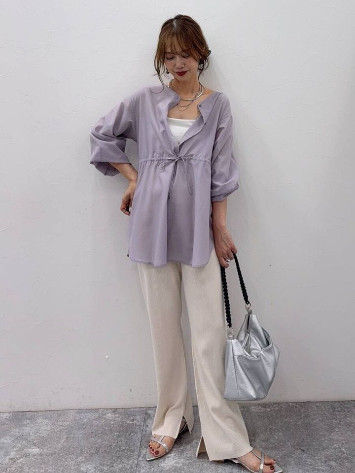 ラベンダー色シアーブラウスと白パンツの女性
