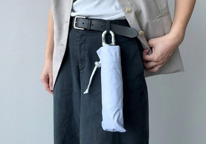 男性がベルトにカラビナ付き折りたたみ傘を装着