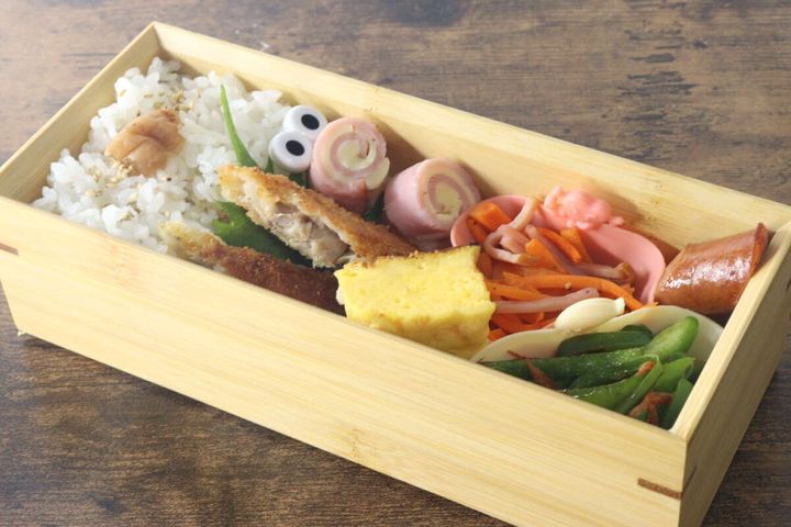 木製のお弁当箱に、おかずカップに入ったおかずが彩り豊かに詰められている