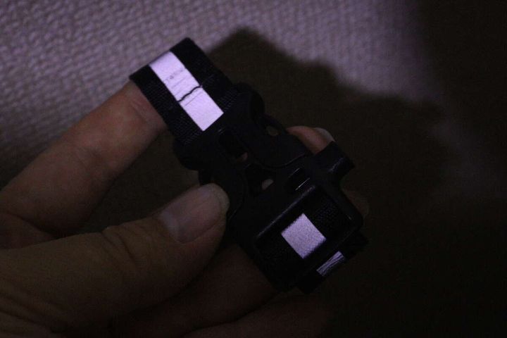 暗闇で光を反射している反射材バックルを手に持っている様子