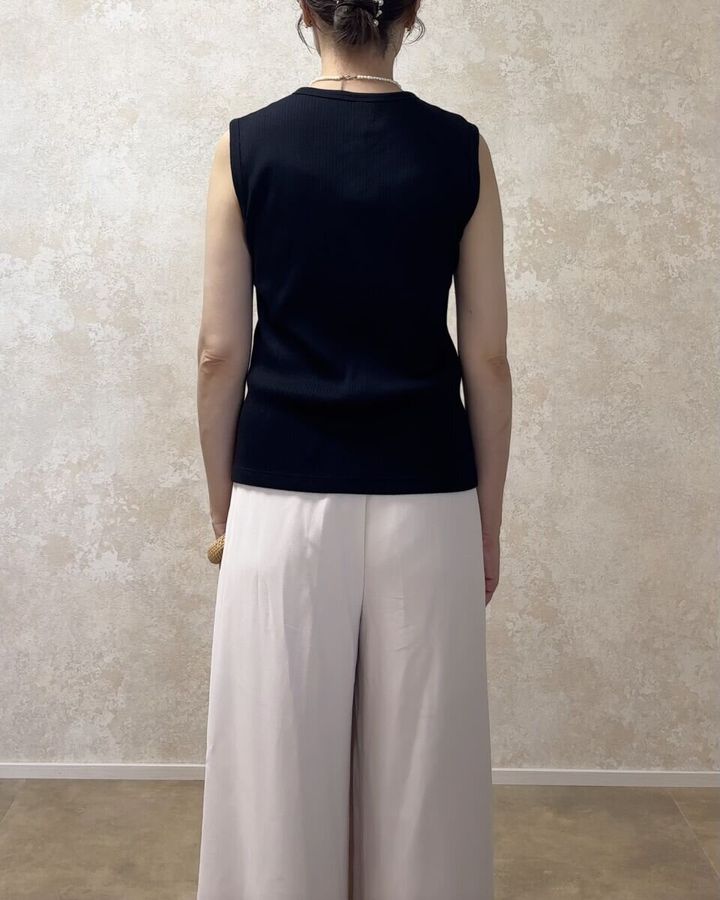 黒いノースリーブトップスとベージュのワイドパンツを着用した女性の後ろ向き全身