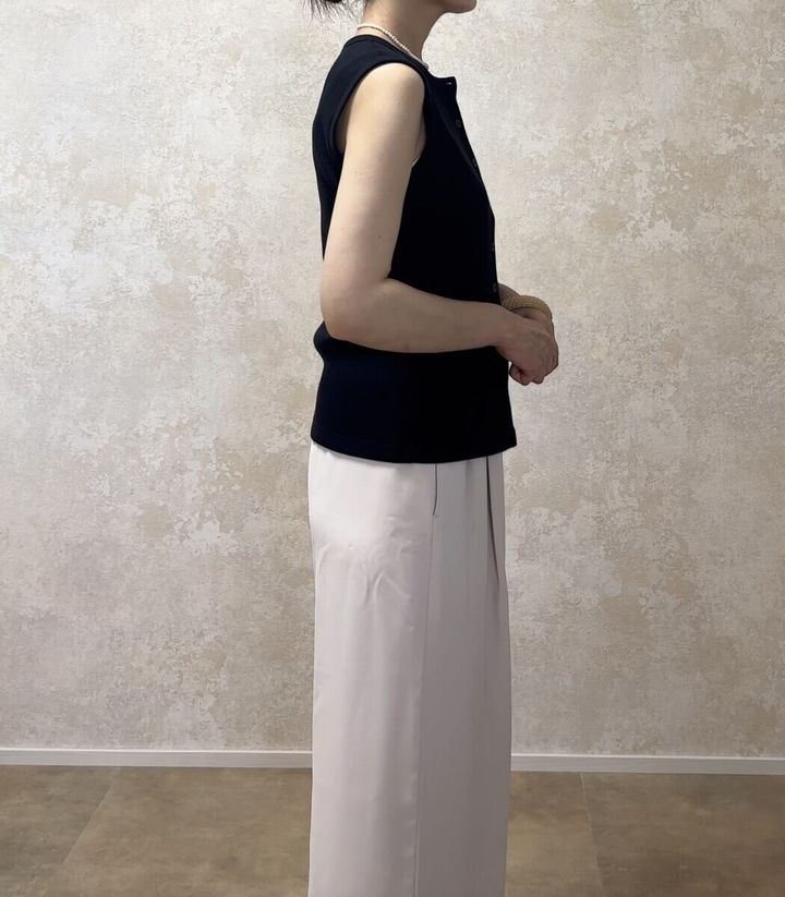 黒いノースリーブトップスとベージュのワイドパンツを着用した女性の横向き全身