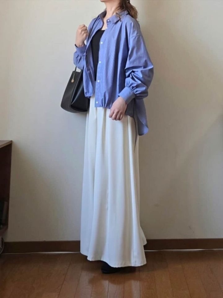 オーバーサイズブルーシャツと白いワイドパンツを着用した女性