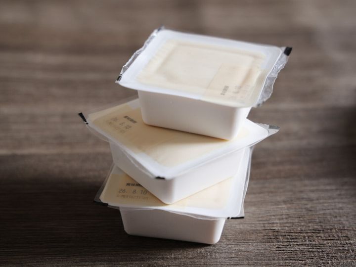木製のテーブルに積み重ねて置かれた、3個パックの充填豆腐