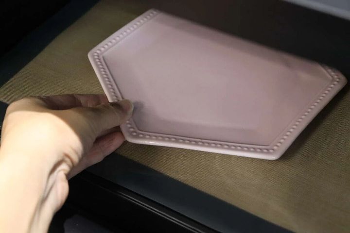 電子レンジマットの上にピンク色の皿を置く手元