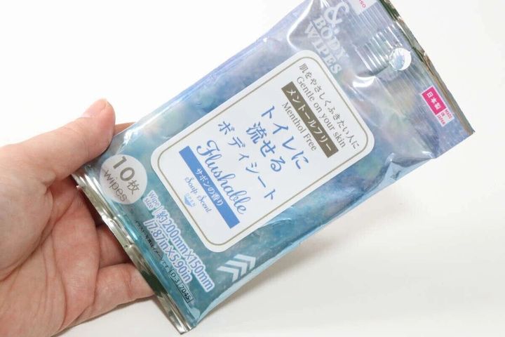 「トイレに流せるボディシート」のパッケージを指で持っている