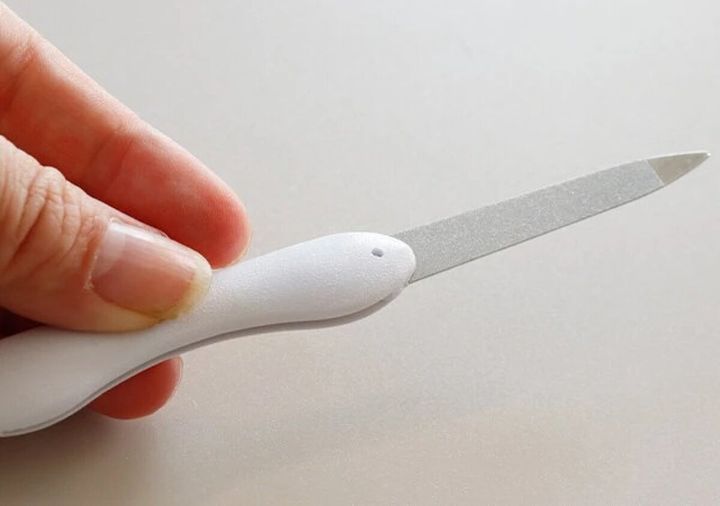 白い折りたたみ爪やすりのやすり部分が展開された状態を指で持っている