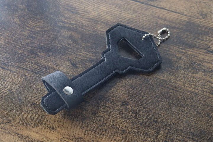 台紙から外された黒い鍵型メガネホルダーが木目調のテーブルに置かれている