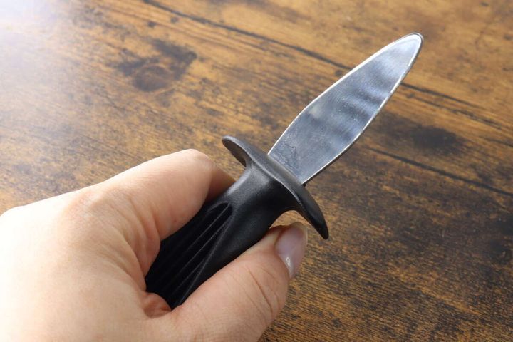 黒い柄の「つば付貝むき」を右手が握っている様子