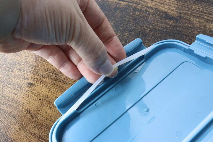 ランチボックスのフタから白いパッキンを指で取り外す手元