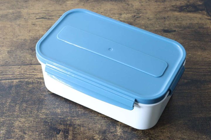 木目のテーブルに置かれた青いフタのダイソーランチボックス本体