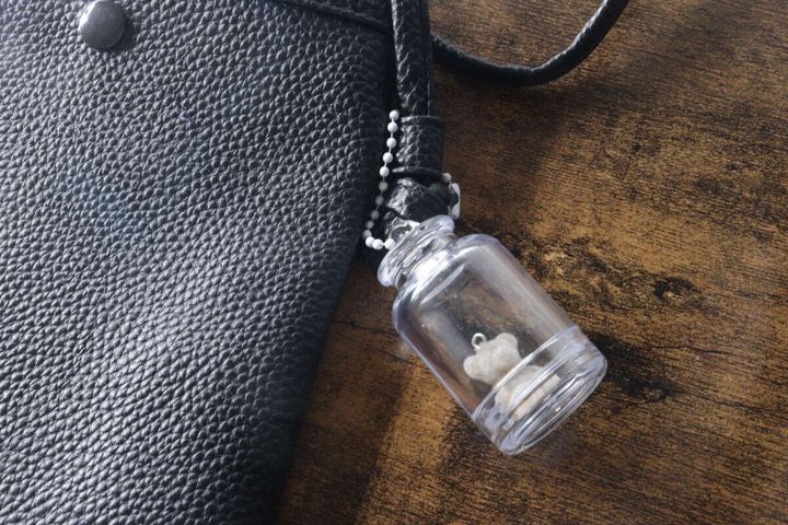 黒いバッグにテディベア入りキーホルダーを付けている