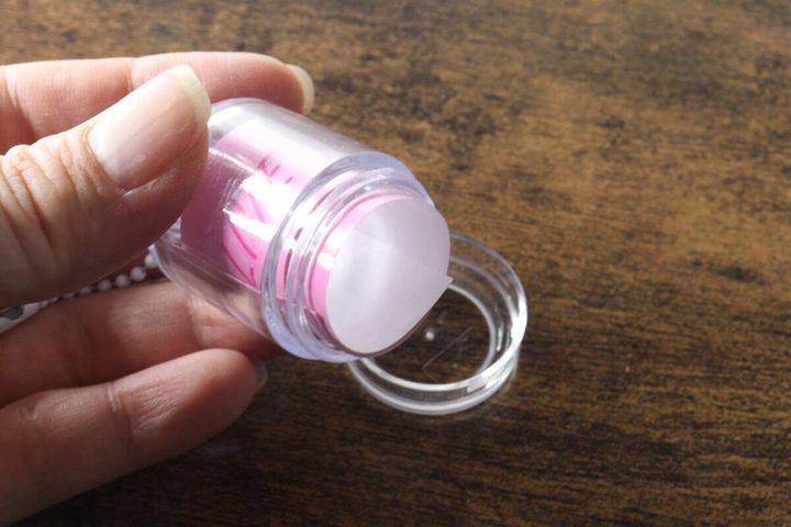女性の手がキーホルダーの底蓋を開けている