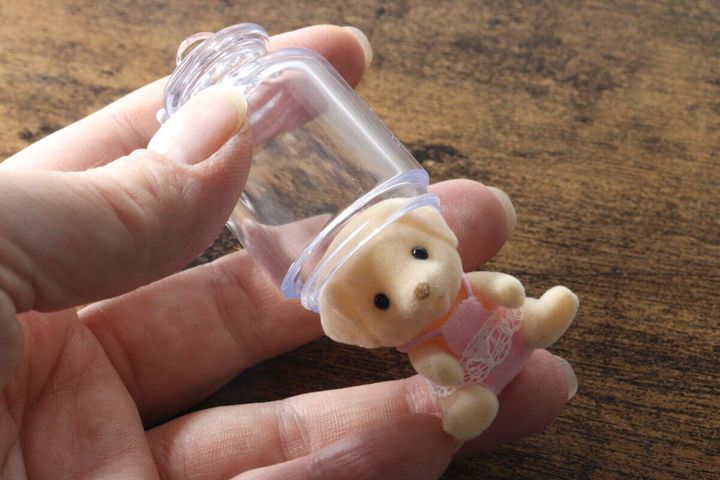 女性の手がキーホルダーからテディベアを取り出す
