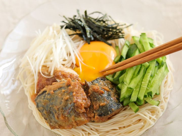 箸でさば味噌煮と卵黄を混ぜようとしている混ぜそうめんのアップ