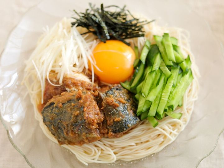 そうめんの上にさば味噌煮、きゅうり、白髪ねぎ、卵黄、刻みのりを盛り付けた混ぜそうめん