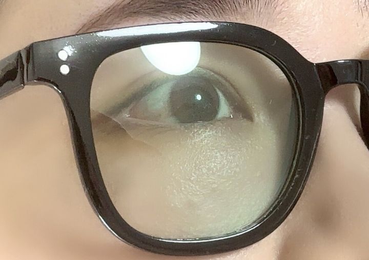 黒いフレームのUVカットサングラスをかけた人の目元が透けて見えるアップ