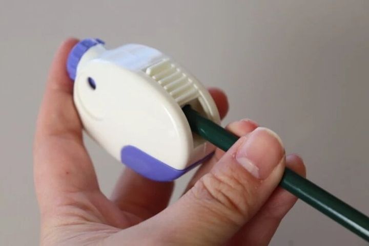 白と紫の鉛筆削りに緑色の鉛筆を差し込んでいる