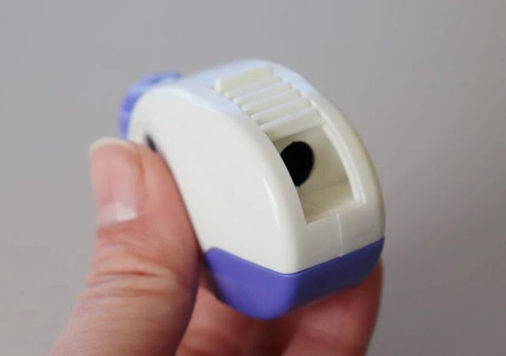 白と紫のコンパクトな鉛筆削りを指で持っている