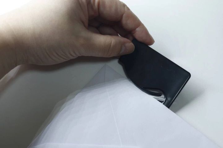 黒い開封カッターで白い封筒の端を開封している