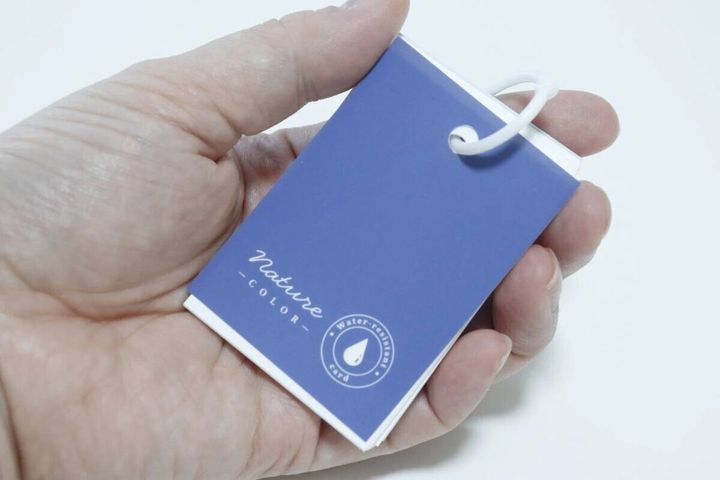 青い表紙の耐水単語帳を手のひらに乗せて持っている