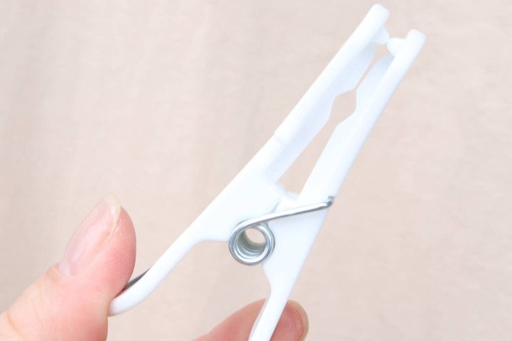 指で白い多機能洗濯ピンチを挟んでいる様子をクローズアップ