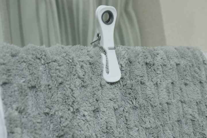 グレーのタオルを白い多機能洗濯ピンチで挟んで固定している