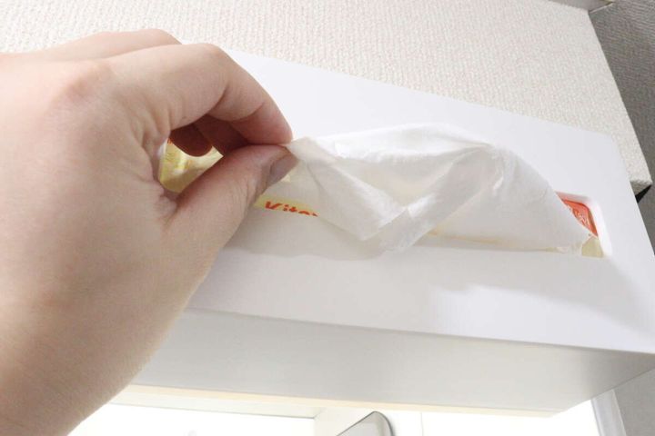 吊戸棚の下に横向きに取り付けられた「2WAYペーパータオルホルダー」からペーパータオルを引き出している女性の手。