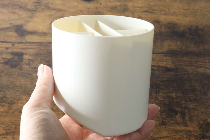 女性の手が白いペンスタンドを縦に持ち底面を見せている