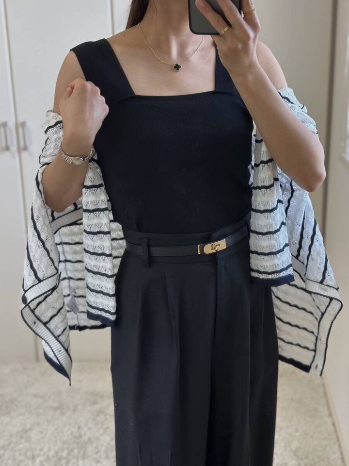 黒いニットインナーとワイドパンツにボーダーカーディガンを肩掛けした女性