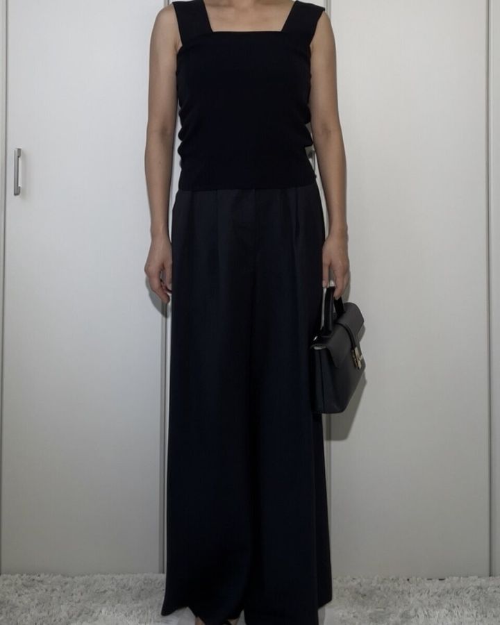 黒いニットインナーをアウトで着用し黒いワイドパンツと合わせたNGコーデの女性