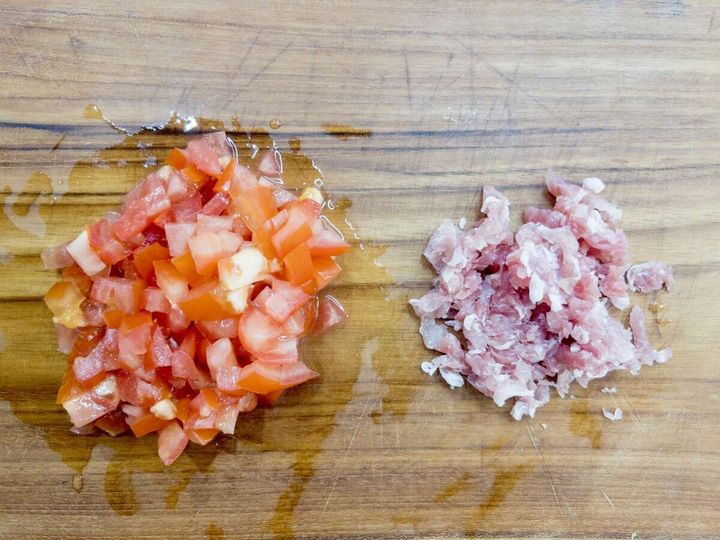 木のまな板に5mm角に切られたトマトと細かく刻んだ生ハムが並べられている