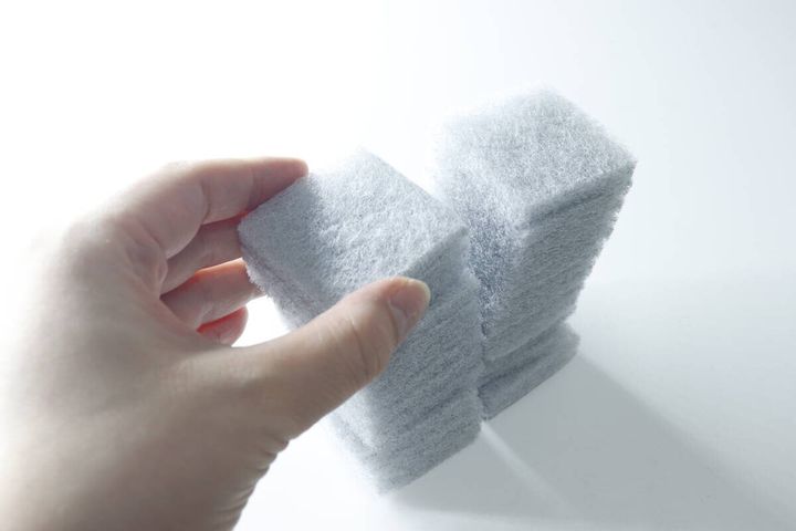 手で積み重ねられた竹炭入りスポンジの束を掴んでいる