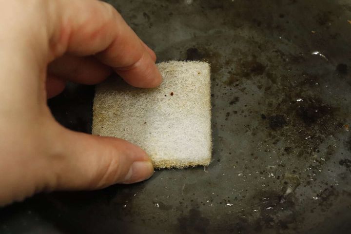 汚れたフライパンを竹炭入りスポンジでこすり洗いしている