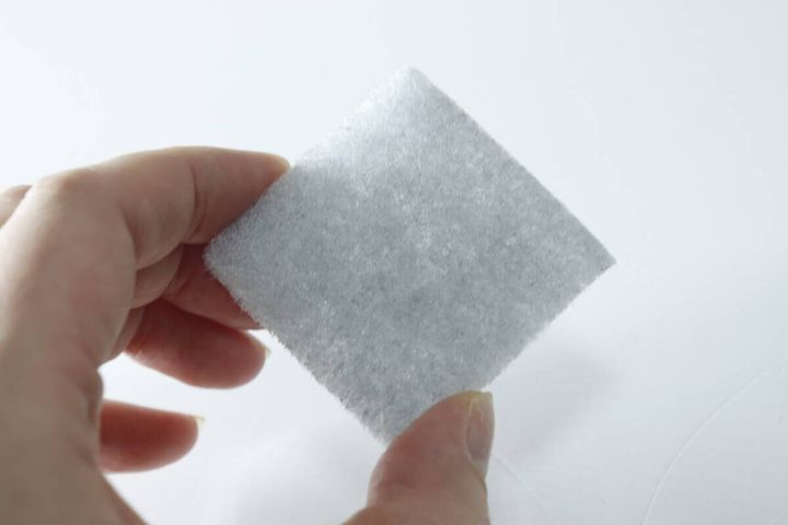 指でダイソー竹炭入りスポンジを1枚つまんで見せている