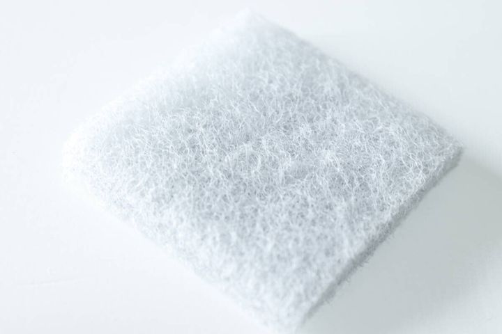 白い背景に置かれた竹炭入りスポンジ1枚のアップ